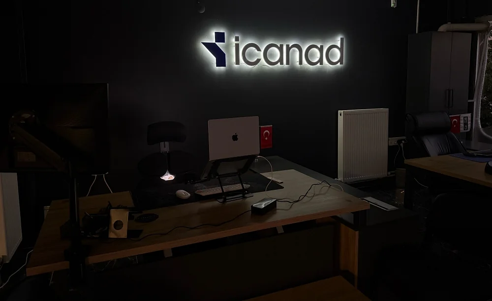 icanad Bartın merkez ofisi — ışıklı icanad tabelası, ayarlanabilir çalışma masaları ve koyu tonlu çalışma alanı